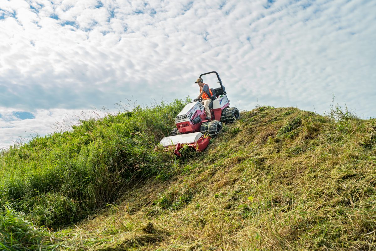 Ventrac slope mower cutting long grass on a steep bank